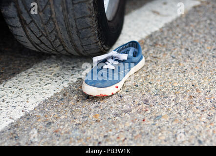 Schuhe im Blut unter dem Auto Räder. Stockfoto