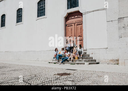 Portugal, Lissabon, 01. Mai 2018: Eine Gruppe von Mädchen im Teenageralter oder Studenten oder Freundinnen sitzen zusammen und auf der Treppe in einer Stadt Straße kommunizieren. Stockfoto