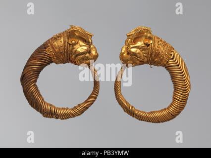 Ohrring mit Leiter der Lion-Griffin. Abmessungen: Als verschlissen: H. 3.4 × W. 3.3 cm (1 5/16 x 1 5/16 in.). Datum: 4.-3.Jh. v. Chr.. Hoops gebildet von Wunde Kabel mit Tierkopf Terminals sind die häufigste Art der Hellenistischen Ohrring. Der Greif ist ein mythischer Geflügelte Tiere, die einen Adler oder einer gehörnten Lion-Kopf haben könnte. Letzteres ist die einzige Art auf Ägyptischer Schmuck gefunden; es wurde vorgeschlagen, dass es mit der Makedonischen Dynastie verbunden war, während die Adler Griffin mit dem Achamenid Perser verbunden war. Der 'Bund' hinter dem Lion's Griffin Kopf ist mit Granulation und Fil eingerichtet Stockfoto