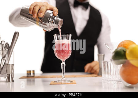 Barkeeper Gießen seine Unterschrift Cocktail in einem Glas auf weißem Hintergrund Stockfoto