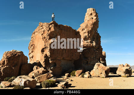 Mann auf einem riesigen Felsen beobachten die Landschaft des Valle de Las Rocas (Tal der Felsen). Bolivien, Südamerika. Stockfoto