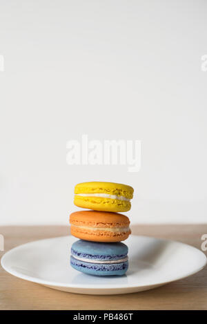 Ein pile-up der Macarons in drei Farben - hellen Backwaren Trio auf einer Platte Stockfoto