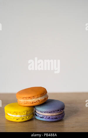 Nahaufnahme mit drei Macarons in verschiedenen Farben sitzen auf einem hölzernen Tisch Stockfoto