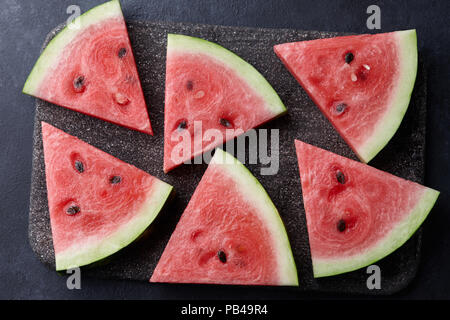 Frisch aufgeschnittenen Wassermelone auf schwarzem Stein, Ansicht von oben Stockfoto
