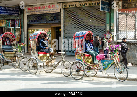 Autofahrer parken Ihren Zyklus Rikschas und warten auf Passagiere in Kathmandu, Nepal Stockfoto