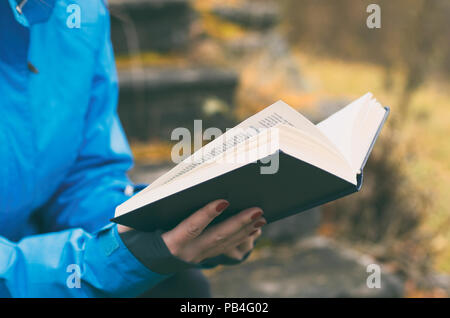 Buch in den Händen der Mädchen schließen Öffnen auf Herbst gelben Hintergrund. Stilisierte Film. Stockfoto