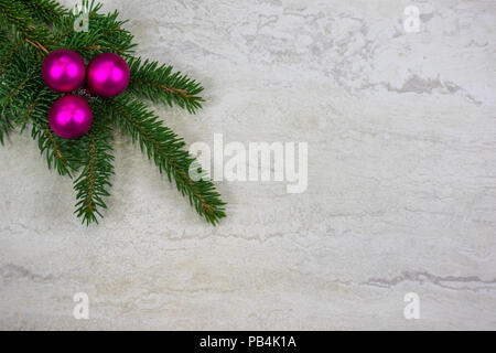 Drei fuchsia Weihnachtsverzierungen auf einer Fichte Ast in der linken oberen Ecke mit Kopie Raum Stockfoto