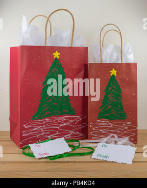 Zwei rote Papier Geschenktüten für Weihnachten dekoriert und für entlang geben mit Tags und grüne und weiße Band bereit Stockfoto