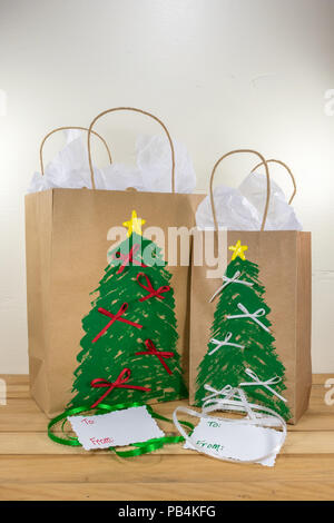 Zwei Papier Geschenktüten für Weihnachten dekoriert und für entlang geben mit Tags und grüne und weiße Band bereit Stockfoto