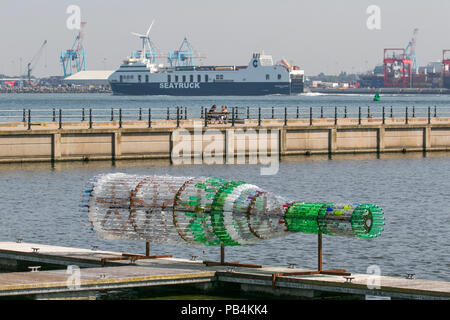 Große übergroße Getränke Flaschenskulptur aus recyceltem, wiederverwendetem, Upcycling-Kunststoff New Brighton, Wallasey. Öffentliche Kunstwerke von Kunststoff-Container aus gebrauchten Flaschen gebaut. Künstler Lulu Quinn schöne und zum Nachdenken anregende „Message in a Bottle“-Upcycling-Flaschenskulptur in Position am Marine Lake. Das 8 m lange Kunstwerk wurde aus 1,500 gebrauchten Getränkeflaschen aus Kunststoff gefertigt, die aus der ganzen Region gesammelt wurden. Stockfoto