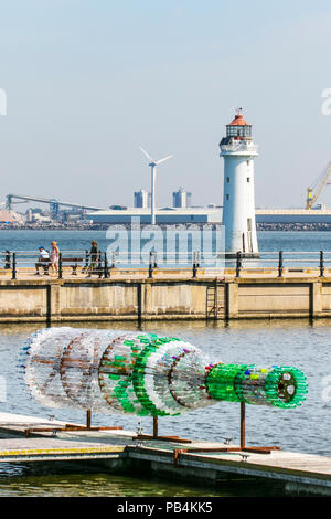 Große übergroße Getränke Flaschenskulptur aus recyceltem, wiederverwendetem, Upcycling-Kunststoff New Brighton, Wallasey. Öffentliche Kunstwerke von Kunststoff-Container aus gebrauchten Flaschen gebaut. Künstler Lulu Quinn schöne und zum Nachdenken anregende „Message in a Bottle“-Upcycling-Flaschenskulptur in Position am Marine Lake. Das 8 m lange Kunstwerk wurde aus 1,500 gebrauchten Getränkeflaschen aus Kunststoff gefertigt, die aus der ganzen Region gesammelt wurden. Stockfoto