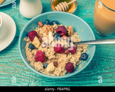 Schüssel Müsli mit Himbeeren und Blaubeeren auf einem blauen Holztisch. Getönten Foto. Stockfoto