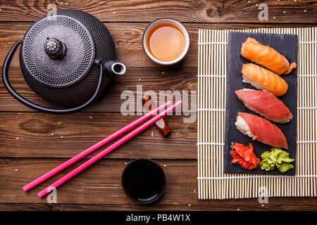 Sushi Set serviert auf grauem Stein Schiefer mit Sojasoße, grau Teekanne und Tasse Tee Stockfoto