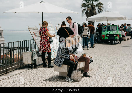 Portugal, Lissabon, 01. Mai 2018: Reifes Paar auf einer Bank sitzen und beobachten eine Karte für weitere Reisen. Stockfoto