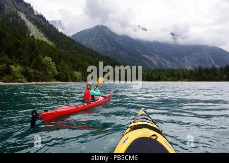 Zwei Kajaks paddeln auf Plansee, Frau in Rot Kajak Kajakfahren auf dem Plansee, Österreich Stockfoto