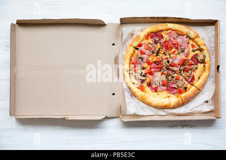 Frische Pizza in einem Karton auf weißem Holz- Tabelle, Ansicht von oben. Von oben, flach. Stockfoto