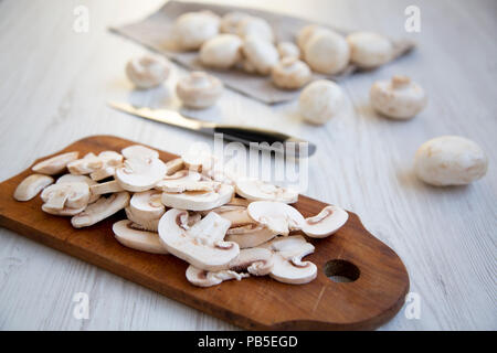 Gehackte Pilze auf rustikalen hölzernen Schneidebrett, Nahaufnahme. Weiß Holz- Hintergrund. Von der Seite. Stockfoto