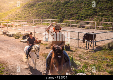 Paar rider Mann und Frau mit braunen und weißen Pferde gehen und den Outdoor Freizeitaktivitäten Aktivität in Ausflug reisen die Berge genießen. Moderne cowbo Stockfoto