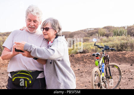 Paar schöne kaukasischen aktiver Erwachsener senior genießen Mountainbike. Alte und Junge Reiter im Outdoor Sport Bikes Tätigkeit zusammen Überprüfung des GPS-m Stockfoto