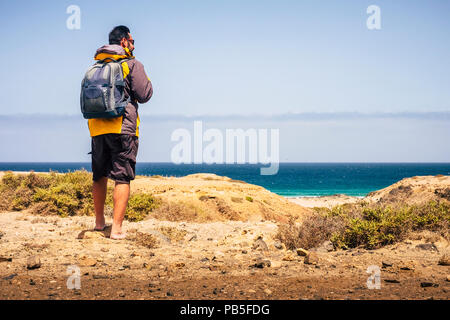 Barfuß trakker traveler Mann auf der Oberseite an der Strand im Hintergrund mit blauem Meer und Himmel. Reiseziel und Freiheit wanderlust Lifestyl Stockfoto