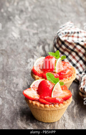 Eierstich Torten mit frischen Erdbeeren und Kalk auf hölzernen Tisch Stockfoto