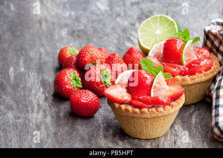 Eierstich Torten mit frischen Erdbeeren und Kalk auf hölzernen Tisch Stockfoto