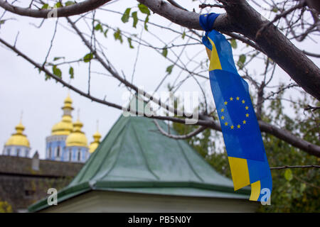 Blau und Gelb Ukraine-EU-Band auf einem Baum in Kiew mit goldenen Kirchenkuppeln im Hintergrund Stockfoto