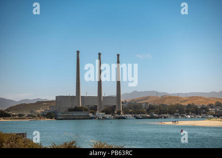 Morro Bay, Kalifornien, USA - 10. Juli 2018: Gas geschlossen Dynergy Kraftwerk im Hafen unter blauem Himmel mit braunen Hügeln auf der Rückseite. Die drei Rauch st Stockfoto
