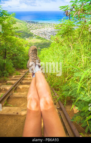 Details von Frau Beine mit Wanderschuhen auf Treppe der populären Hawaiian wandern, Koko Head treppen Wanderung. Die malerische Landschaft der Insel Oahu, Hawaii, USA. Vertikale erschossen. Stockfoto