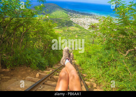 Beine von Reisenden am Anfang von 1048 Schritte der populären Hawaiian wandern sitzend, Koko Head treppen Wanderung. Wanderschuhe auf Treppe von malerischen Trekking in Oahu, Hawaii, USA. Freiheit Konzept. Stockfoto