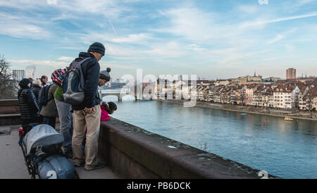 Basel, Schweiz, 25. Dezember 2017: Touristen beobachten Sie die Ufer des Rheins im Zentrum der Stadt an einem Wintertag Stockfoto