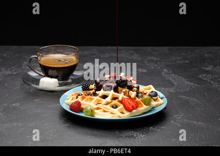 Foto Tasse schwarzen Kaffee mit Zucker mit Wiener Waffeln mit Erdbeeren, Himbeeren, Stachelbeeren und Schokolade Stockfoto