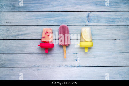 Verschiedene hausgemachte Popsicle, gefroren Dessert auf Blau blass Holz- Hintergrund Stockfoto