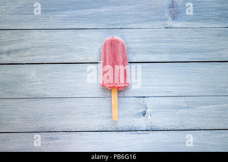 Rote Erdbeere popsicle auf Blau Holz Hintergrund Stockfoto