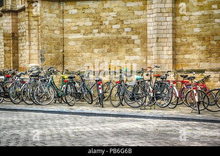 Fahrräder überall entlang der Backsteinkirche Wand geparkt in Breda, Niederlande Stockfoto