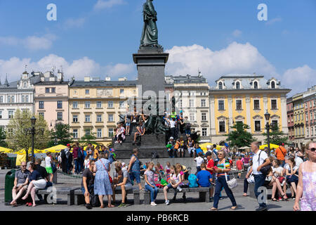 Polnische Kinder sitzen und ruhen auf dem Adam Mikiewicz Denkmal auf dem Hauptplatz in Krakau, Polen, Europa. Stockfoto