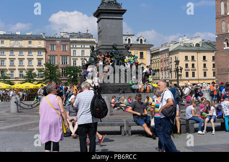 Polnische Kinder sitzen und ruhen auf dem Adam Mikiewicz Denkmal auf dem Hauptplatz in Krakau, Polen, Europa. Stockfoto