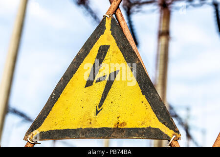 Close-up Alten rostigen Dreieck Metallplatte mit hoher Spannung Warnzeichen. Kraftwerk mit Transformatoren und die Verteilung von Strom. Halten Stockfoto