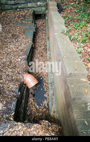 Alte open Düker mit alten Steinen und einem Kunststoff PVC Abwasserrohr gebaut. Stockfoto