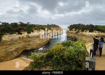 Zwei Leute, die in der Aussicht auf Loch Ard Gorge an einem bewölkten Tag, Port Campbell National Park, Great Ocean Road, Victoria, Australien Stockfoto