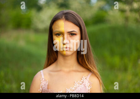 Nahaufnahme Porträt einer schönen jungen Mädchen in weißen Akazie im Frühjahr die Hälfte Gesicht goldene Make-up Stockfoto