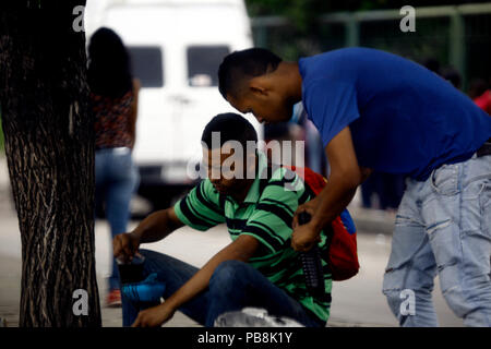 Juli 26, 2018 - Valencia, Carabobo, Venezuela - Junge informellen Verkäufer von Öl für ausrangierte Fahrzeuge, laden 1-Liter Container auf öffentlichen Straßen zu verkaufen. Die Wirtschaftskrise führt Bürger verworfen, Schmiermittel oder besser bekannt als "Olivenöl" zu ihren Fahrzeugen, die Sie zu einem Preis von Bs erhalten verbrannt. 200.000,- oder pro Liter (neuen Kegel Bs.2,oo) statt des Wertes eines neuen, hat eine Gebühr von Bs. 25.000.000 oder pro Liter (neuen Kegel Bs. 250, oo). Die Situation ist, dass der Käufer nicht den Ursprung des Öls wissen, wenn es eine Mischung aus 15-40 Schmierstoffe mit 20-50, mineralischen Ursprungs Stockfoto