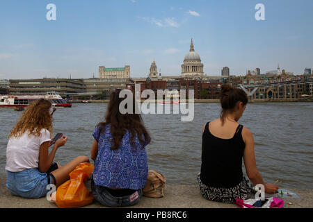 London, Großbritannien, 27. Juli 2018. UK Wetter: Drei Frauen sitzen auf der Kante der Themse mit Blick auf die St Paul's Kathedrale an einem sehr heißen und schwülen Tag in der Hauptstadt. Credit: Dinendra Haria/Alamy leben Nachrichten Stockfoto