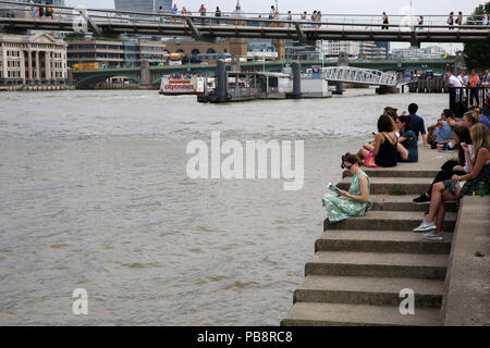 London, Großbritannien, 27. Juli 2018. UK Wetter: Touristen und Einheimische, die das Londoner sitzt auf der Kante der Themse mit Blick auf die St Paul's Kathedrale an einem sehr heißen und schwülen Tag in der Hauptstadt. Credit: Dinendra Haria/Alamy leben Nachrichten Stockfoto