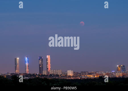 Madrid, Spanien. 27. Juli, 2018. Der Mond scheint in der Nähe der vier Türme Wolkenkratzer bei einer totalen Mondfinsternis, die längste Sonnenfinsternis des Jahrhunderts, mit einer Dauer von 1 Stunde 43 Minuten und 35 Sekunden. In Madrid, Spanien. Credit: Marcos del Mazo/Alamy leben Nachrichten Stockfoto