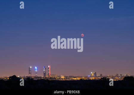 Madrid, Spanien. 27. Juli, 2018. Der Mond scheint in der Nähe der vier Türme Wolkenkratzer bei einer totalen Mondfinsternis, die längste Sonnenfinsternis des Jahrhunderts, mit einer Dauer von 1 Stunde 43 Minuten und 35 Sekunden. In Madrid, Spanien. Credit: Marcos del Mazo/Alamy leben Nachrichten Stockfoto