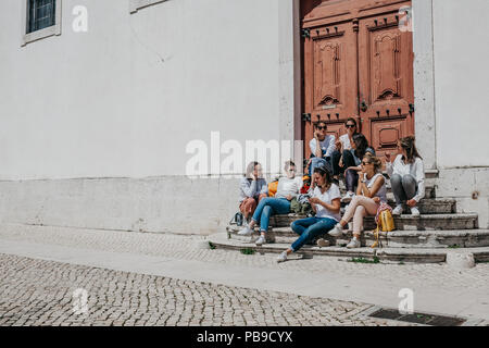 Portugal, Lissabon, 01. Mai 2018: Eine Gruppe von Mädchen im Teenageralter oder Studenten oder Freundinnen sitzen zusammen und auf der Treppe in einer Stadt Straße kommunizieren. Stockfoto