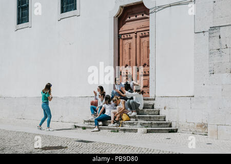 Portugal, Lissabon, 01. Mai 2018: Eine Gruppe von Mädchen im Teenageralter oder Studenten oder Freundinnen sitzen zusammen und auf der Treppe in einer Stadt Straße kommunizieren. Stockfoto