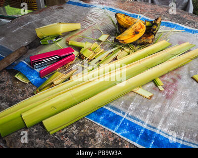 Vorbereitungen für einen Balinesischen canang Sari bietet aus Palmblättern, Heftklammern, Banane. (Sidemen, Bali, Indonesien). Stockfoto