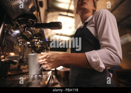 Frau im Cafe tragen Schürze, einen Kaffee in der Maschine. Barista die Zubereitung von Kaffee auf Kaffeemaschine Maschine. Stockfoto